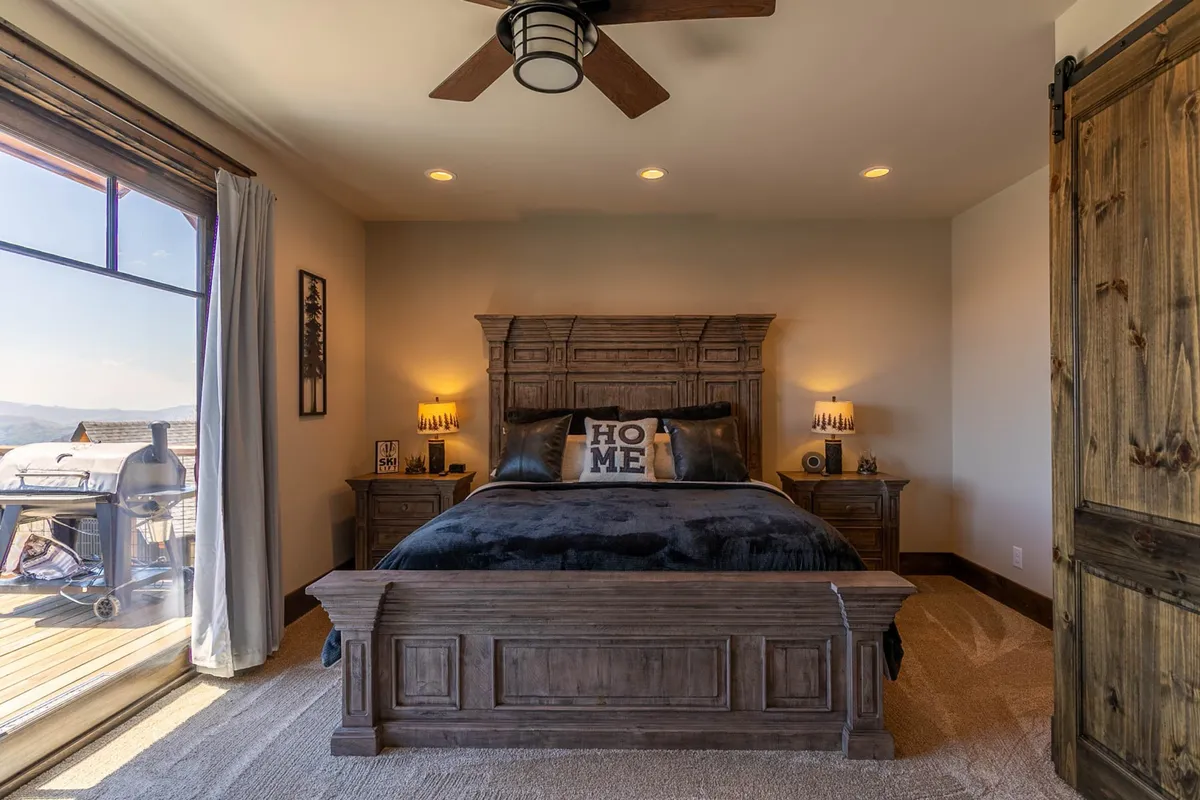A cozy bedroom with a wooden bed frame, decorative pillows, and a window offering a peaceful view. The atmosphere is inviting, designed for relaxation and restful sleep.