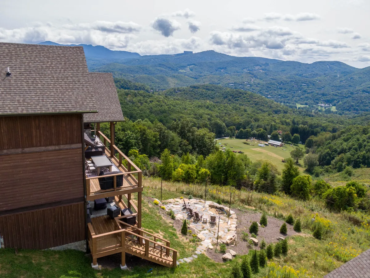 This image captures a tranquil exterior scene with a landscaped garden, a comfortable outdoor seating area, and a panoramic view of the mountain range. The setting is ideal for outdoor dining, relaxing by the fire pit, or enjoying the natural beauty that surrounds Bear Haven Hideaway.