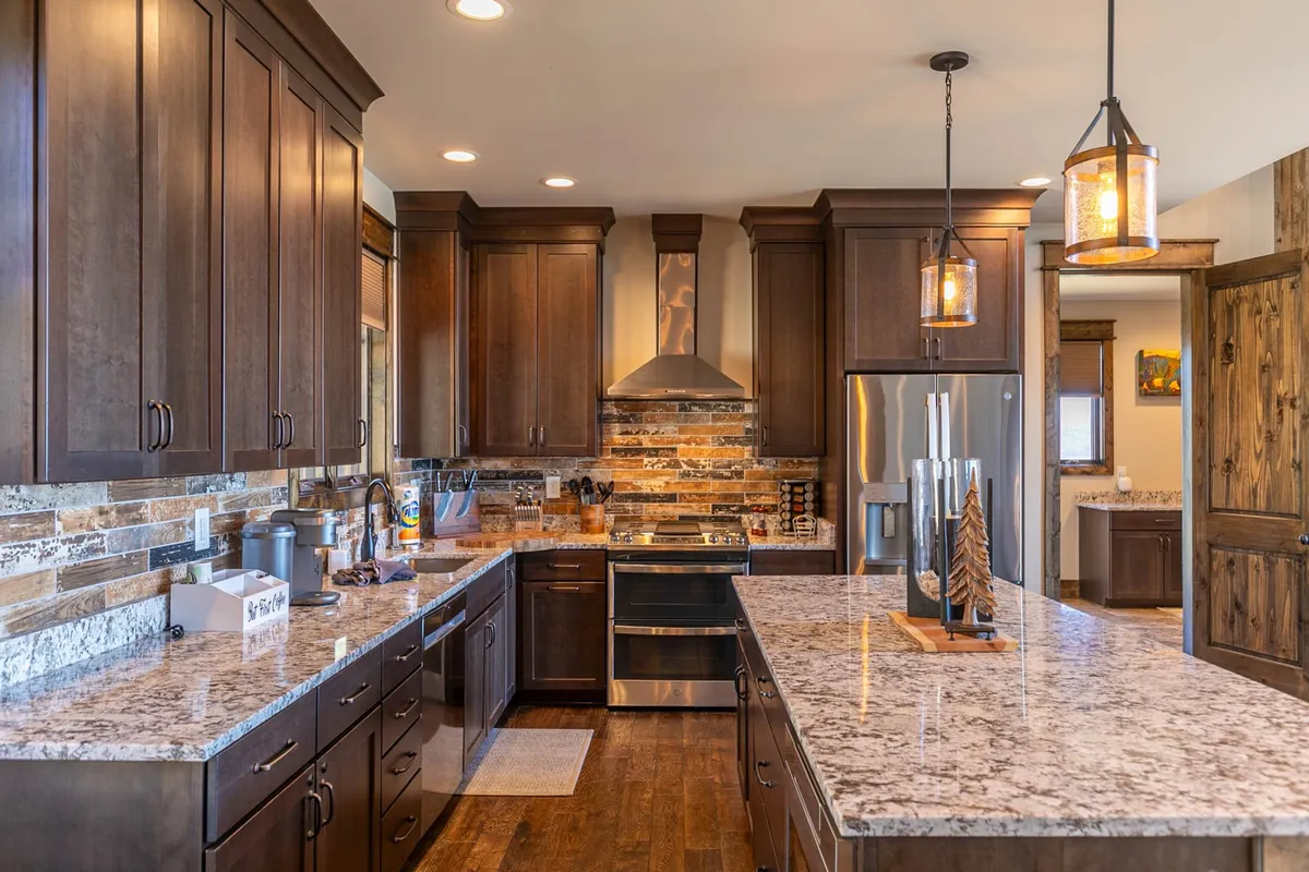 A gourmet kitchen shines with its granite countertops, wooden cabinets, modern appliances, and thoughtful lighting. The layout invites guests to gather, cook together, or enjoy casual conversation at the island.